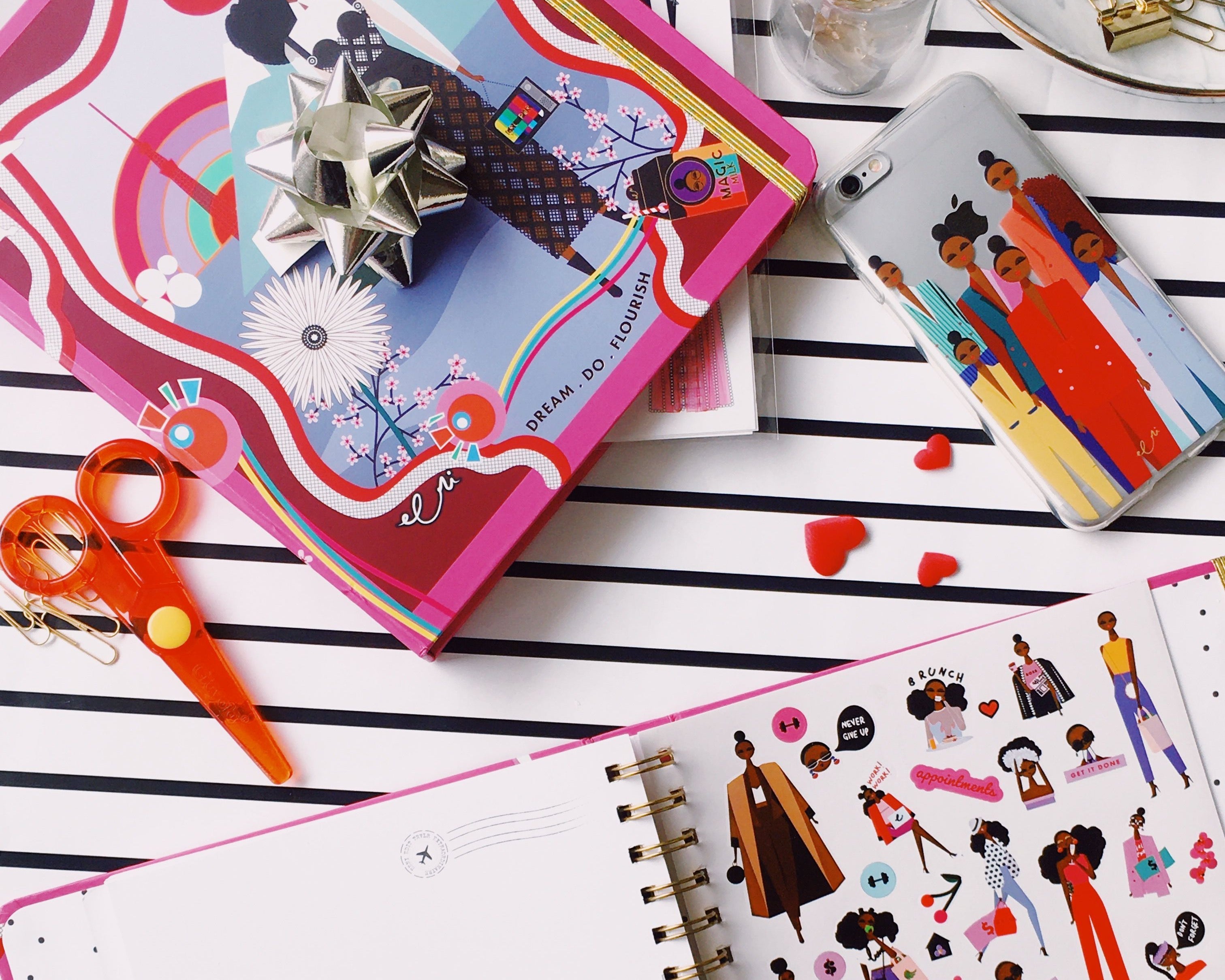 Open notebook with illustrated pages on a striped surface with stationery items.